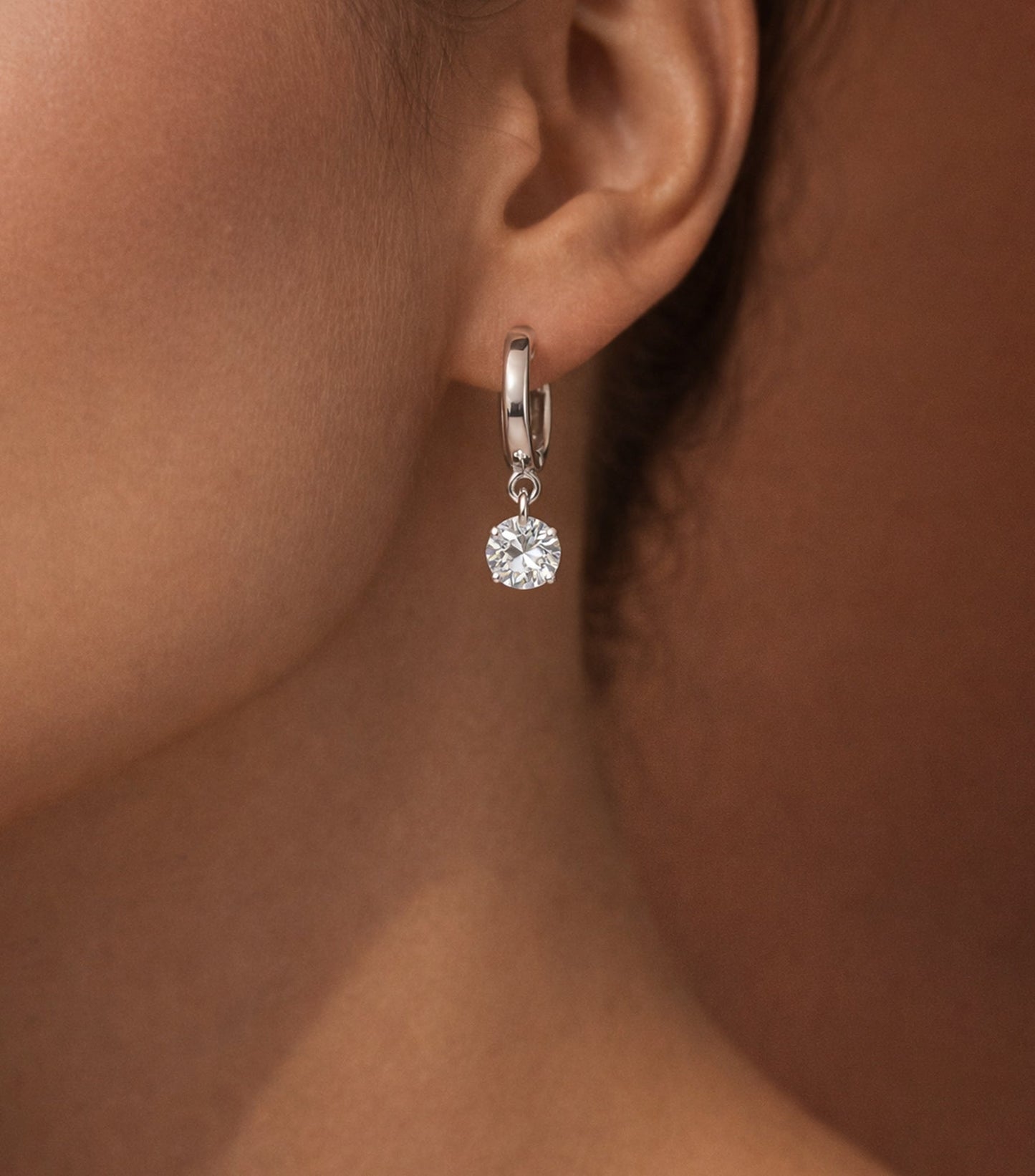 Close-up of a diamond earring on an ear with a neutral background
