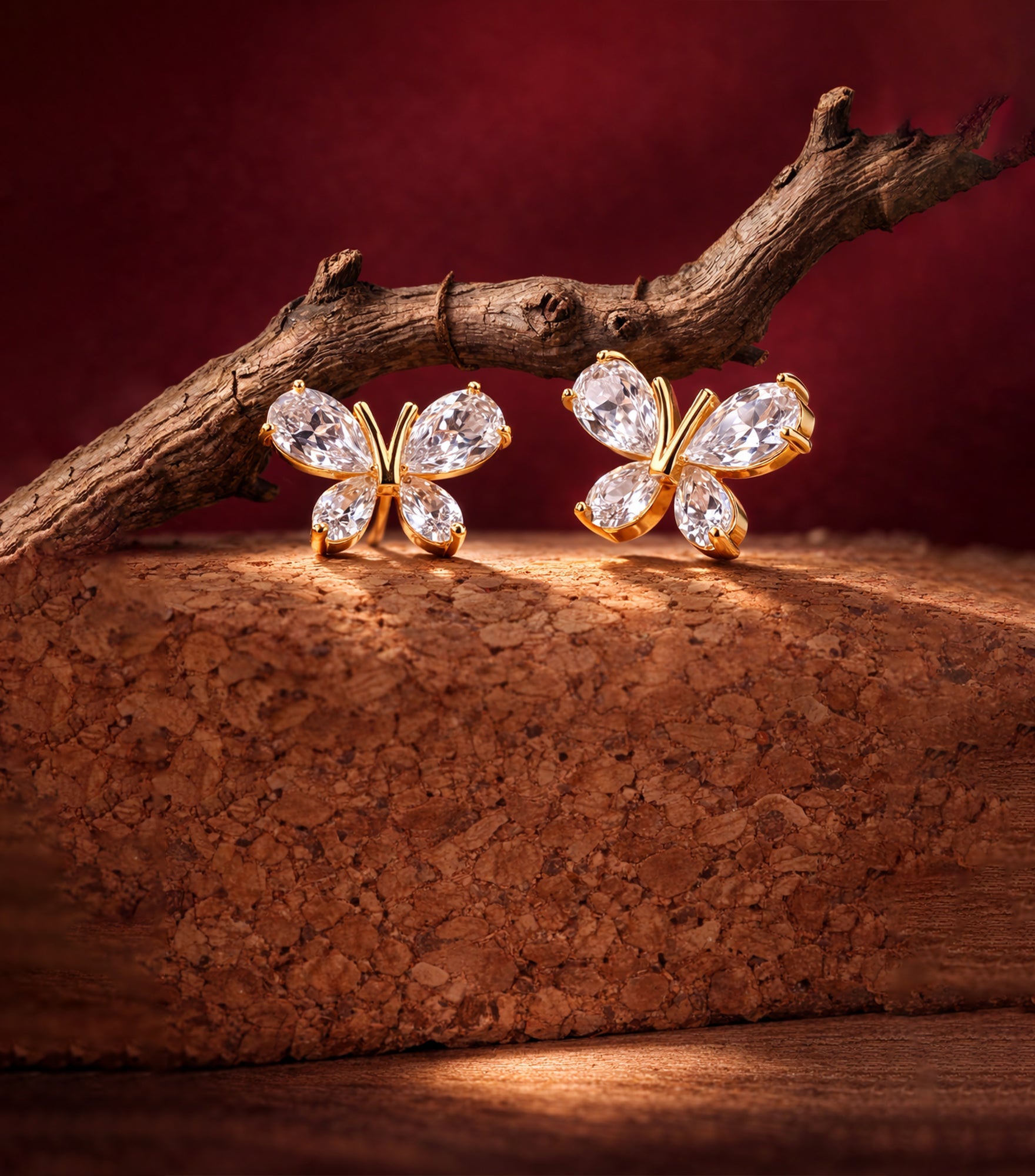 Butterfly-shaped earrings with clear stones on a wooden surface with a dark background