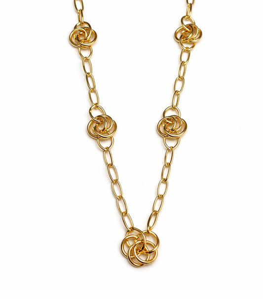 Gold chain necklace with floral links on a white background
