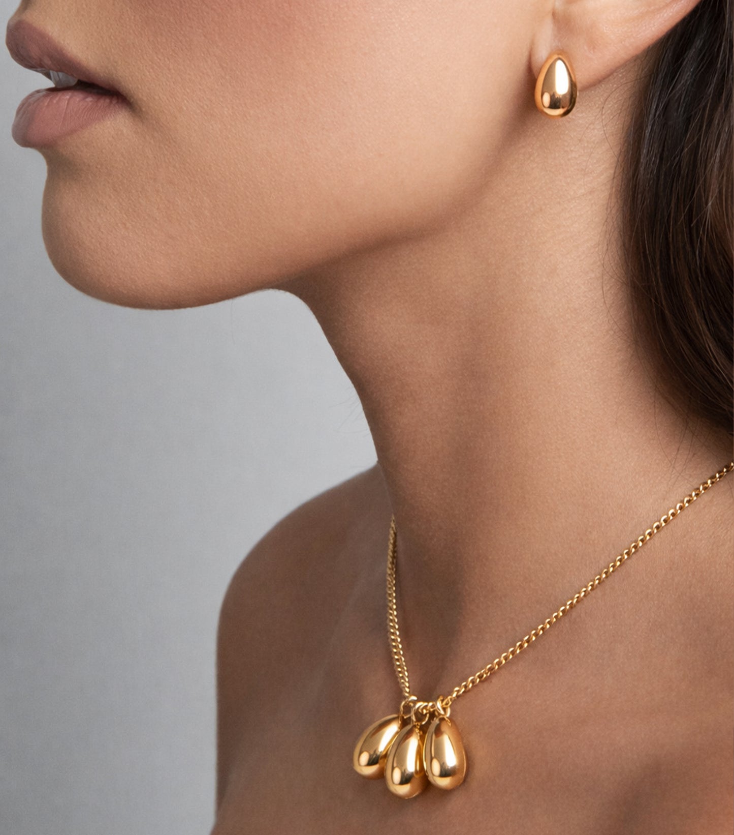 Gold necklace and earrings on a neutral background