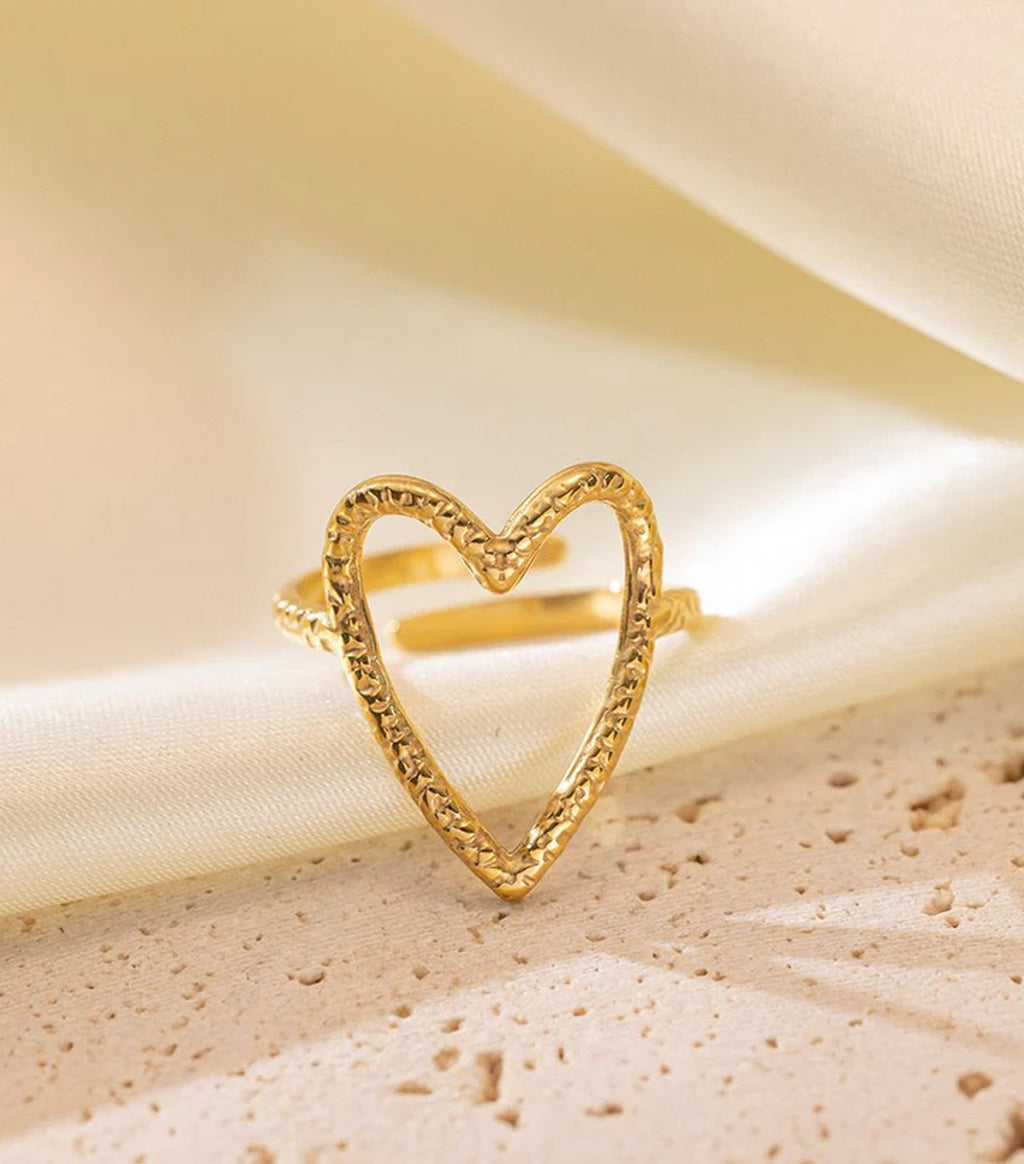 Gold heart-shaped ring on a beige fabric background