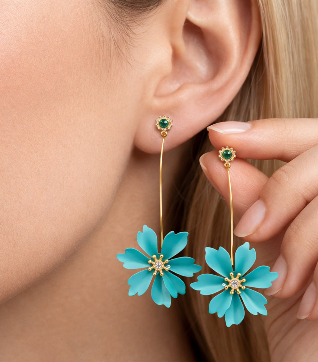 Close-up of a woman wearing turquoise flower earrings with gold accents.

